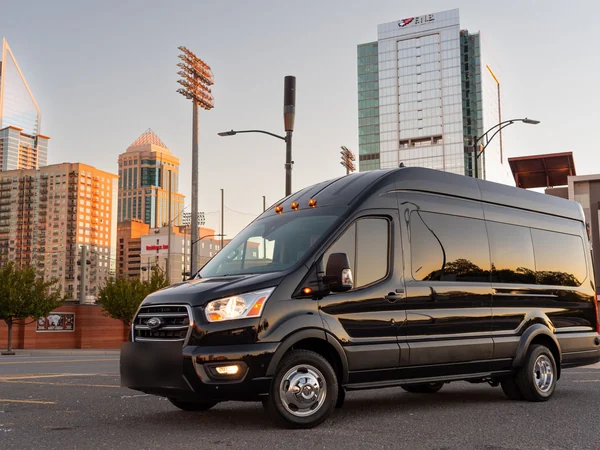 Black Ford Transit passenger van on a city street at dusk
